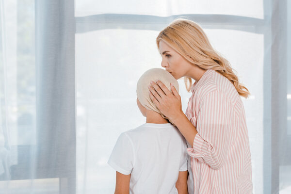 Mother kissing head of child cancer patient